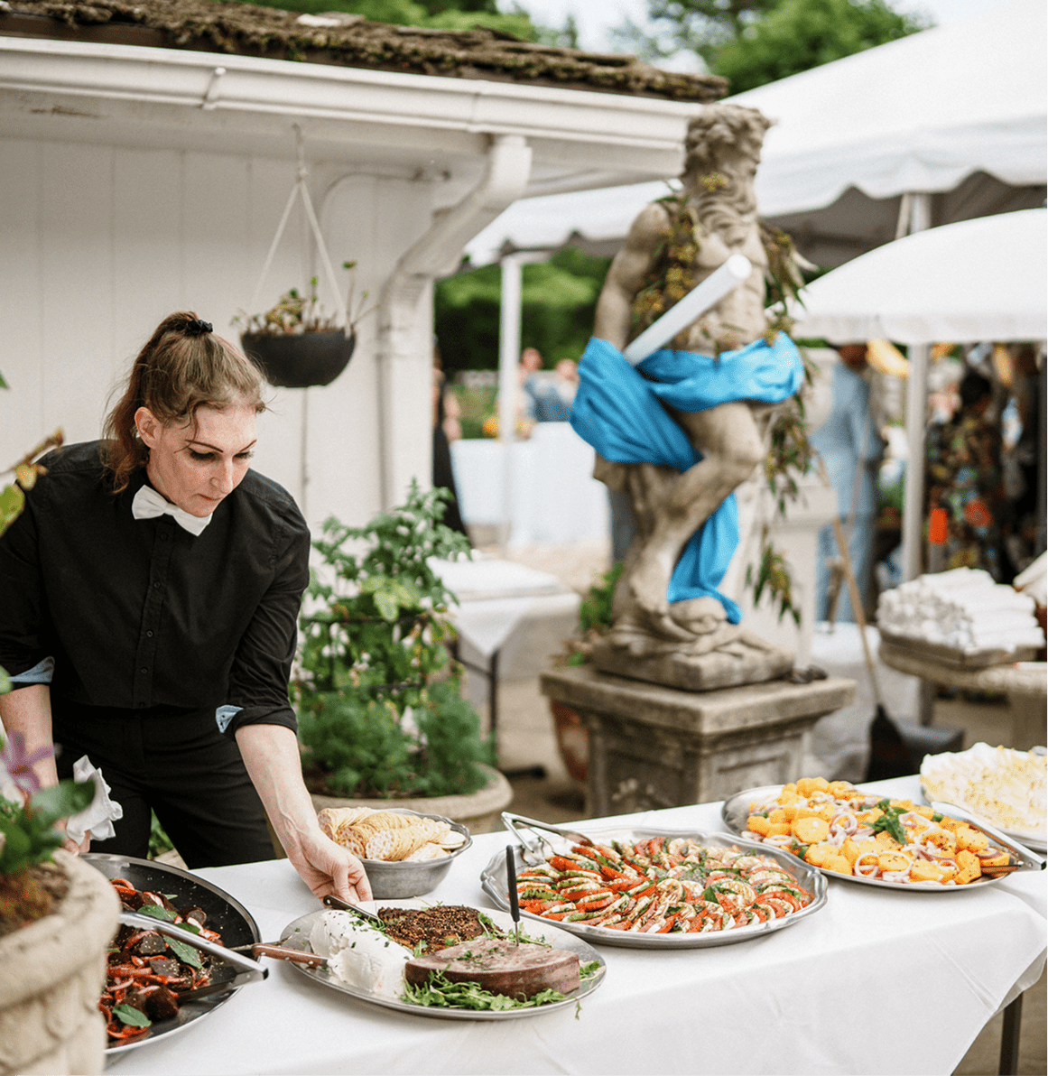 Caterer arranging food on outdoor buffet table