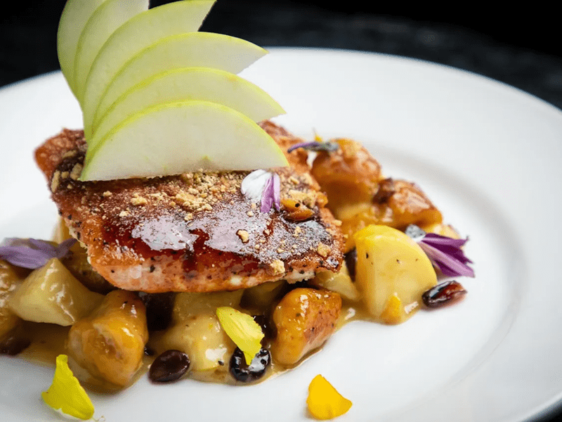 Seared fish with roasted vegetables and sliced green apples.
