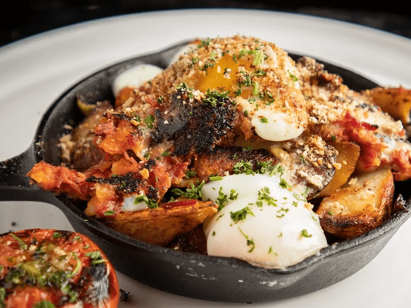 Hearty baked dish with cheese and herbs in a black skillet.