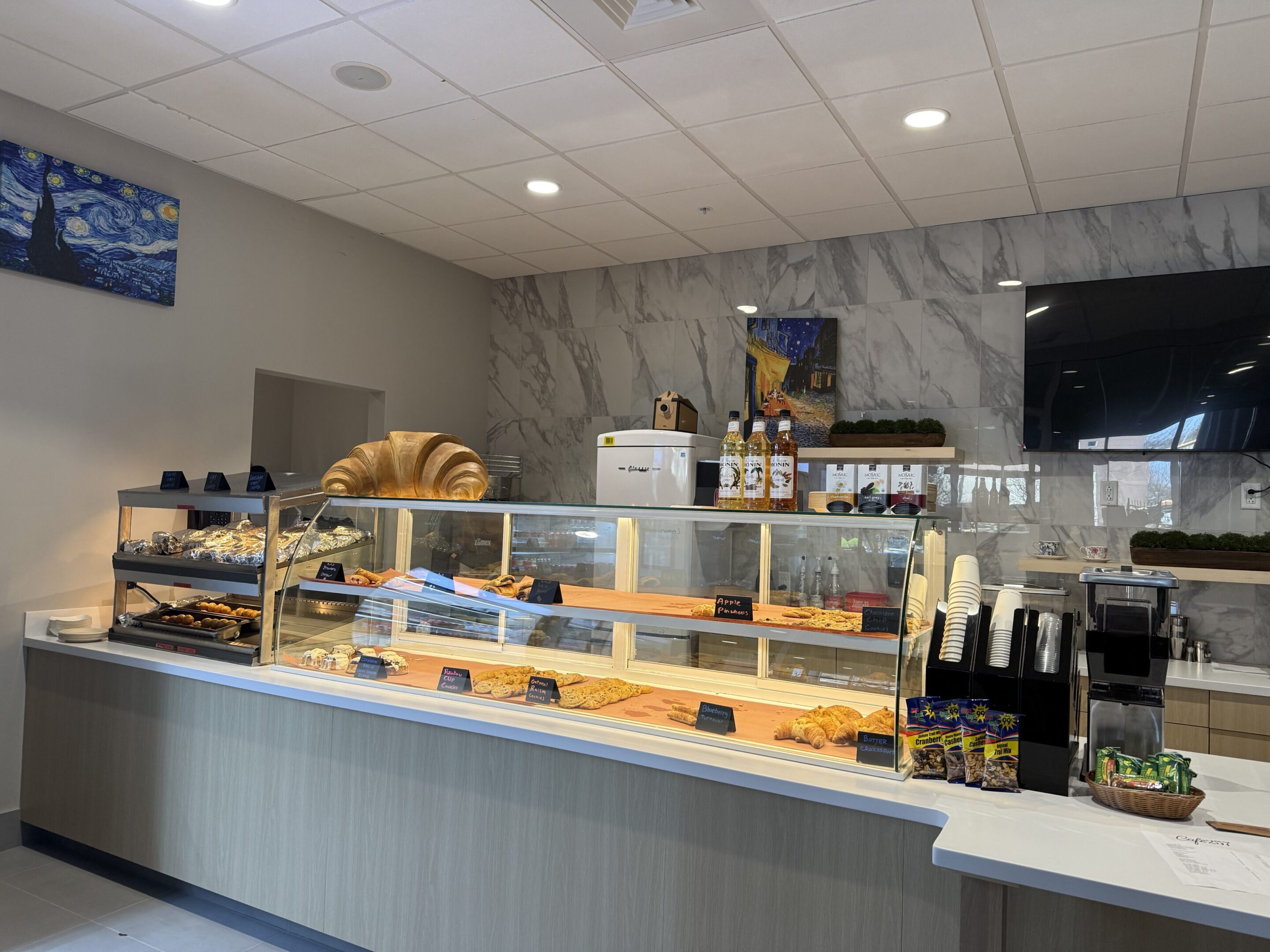 Modern bakery counter with pastries and bread on display.