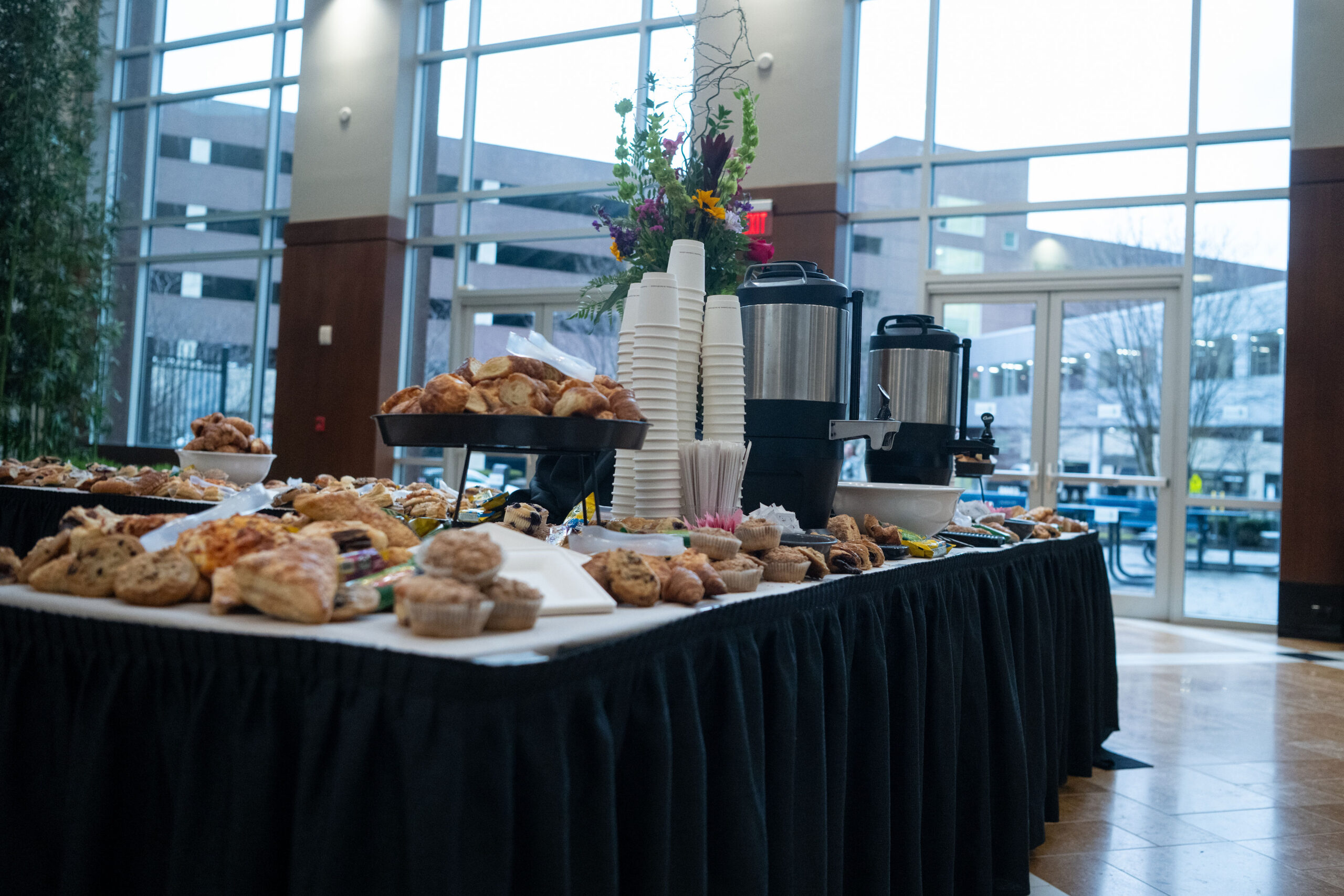A table filled with assorted pastries and coffee cups in a bright room.