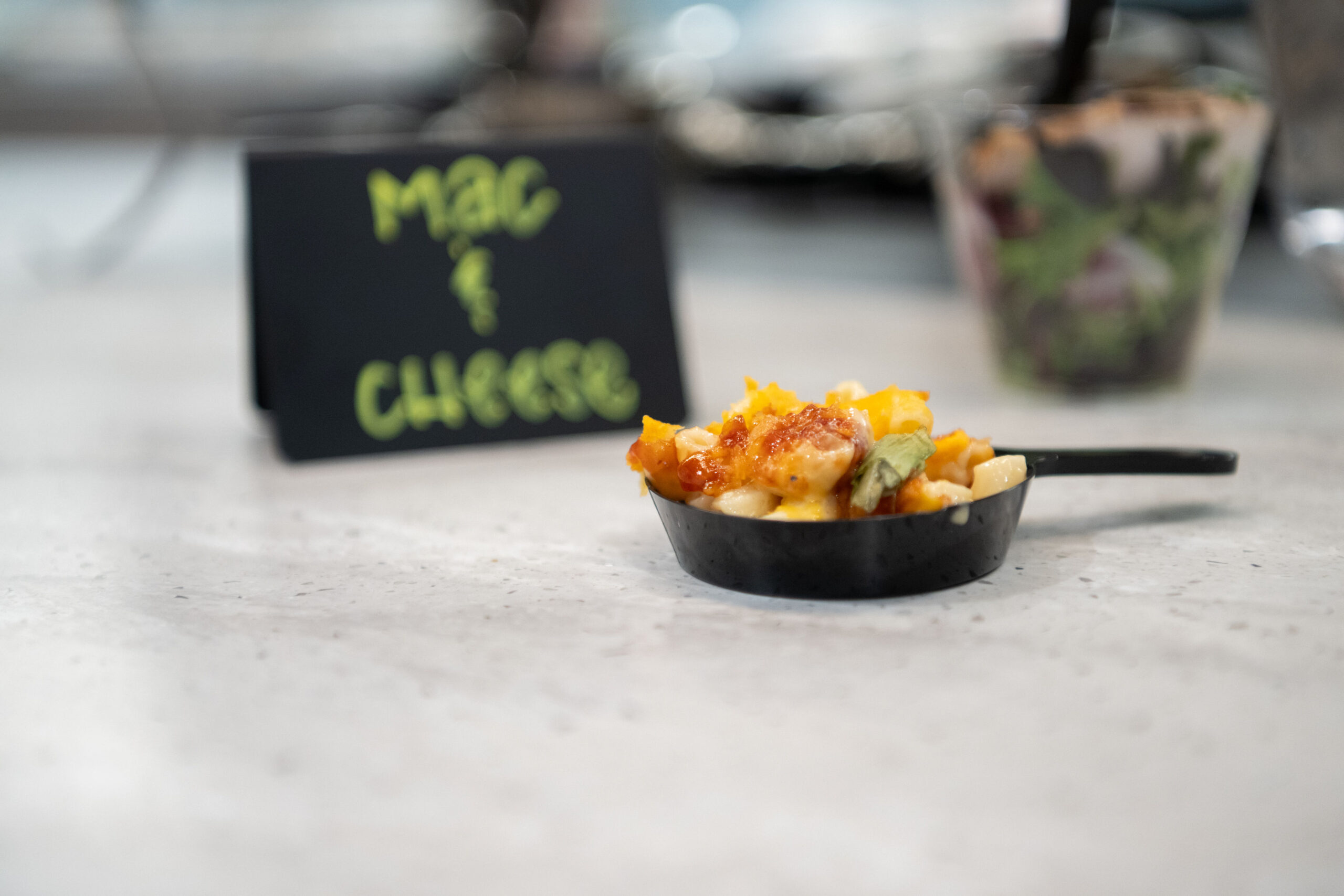 A small dish of mac and cheese with a chalkboard sign.