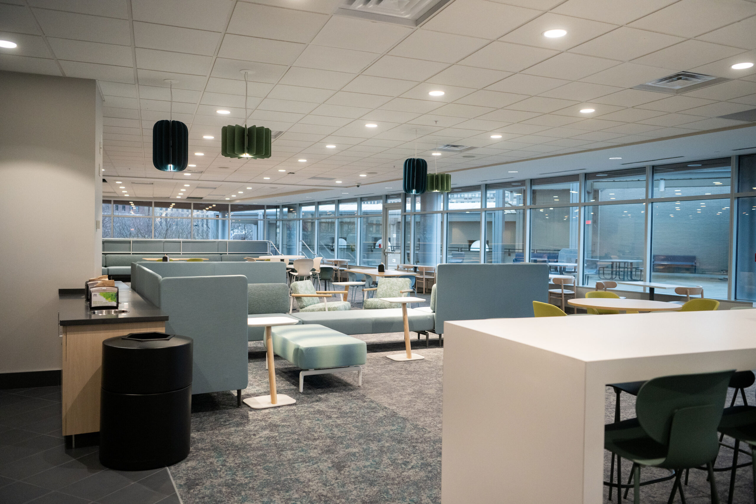 Modern office space with desks, chairs, and carpeted floors under bright ceiling lights.